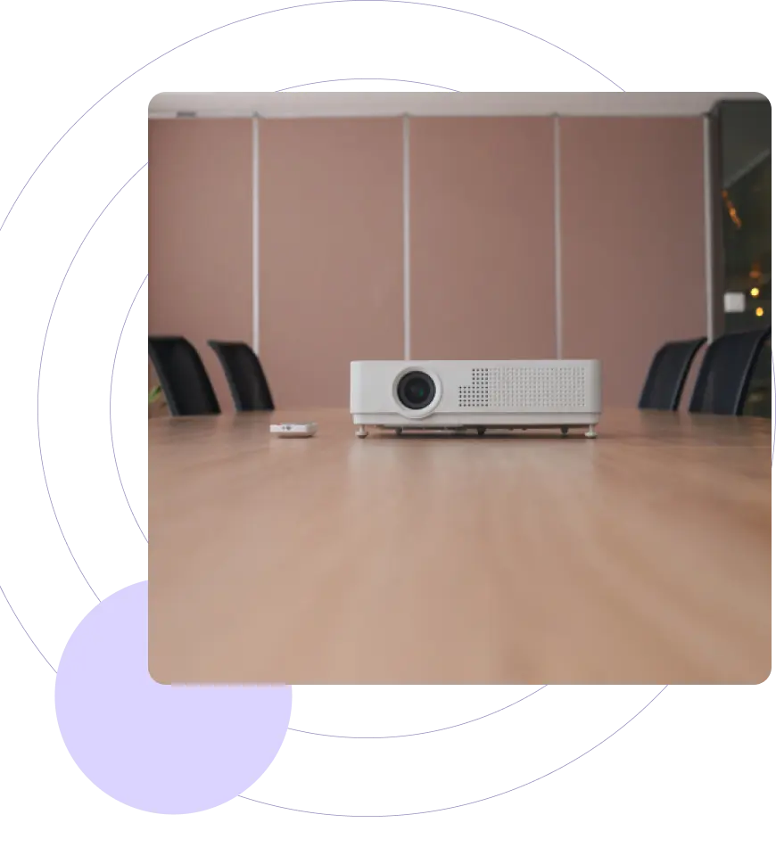 Projector on a conference room table with chairs around it